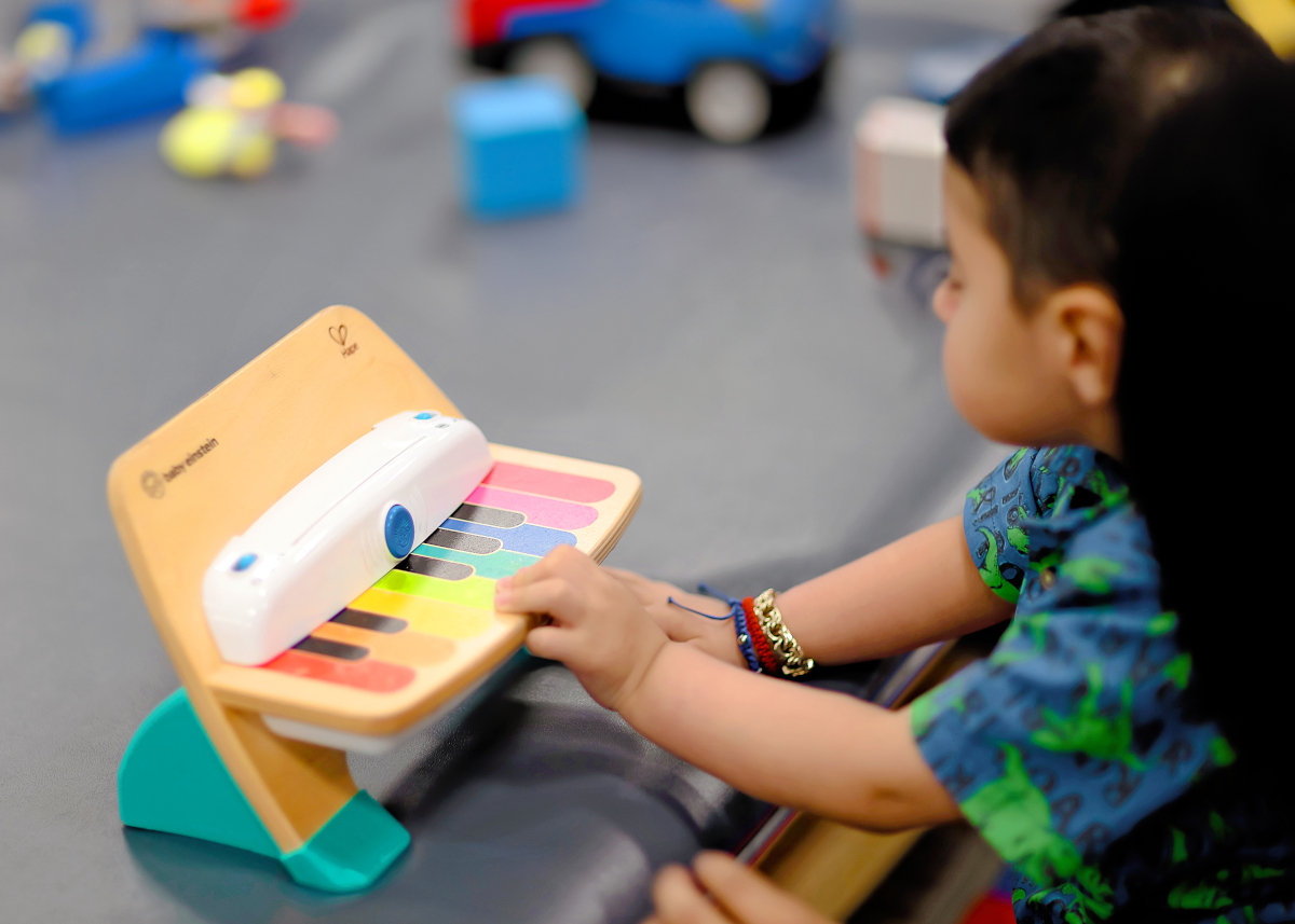 A little boy plays a small toy piano in front of him.