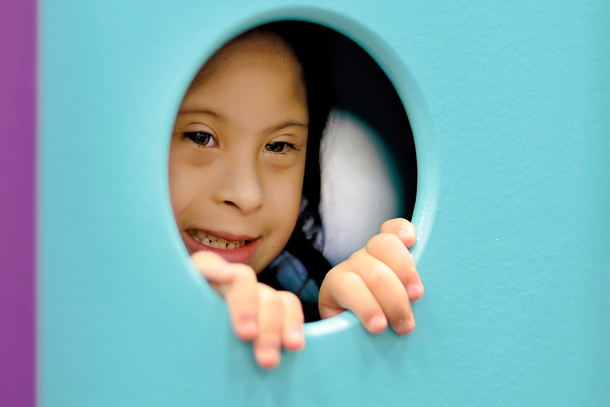 Little girl peeks through a window in a playhouse